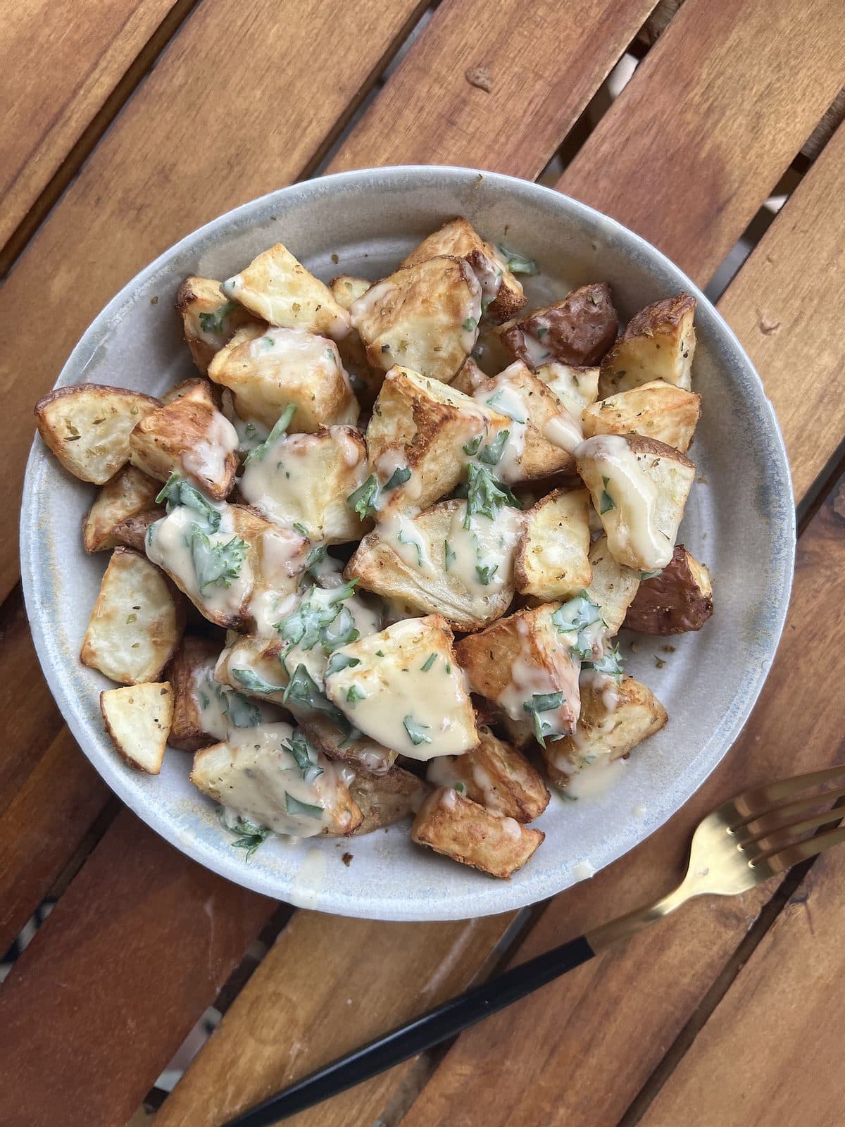 bowl of crispy air fried potatoes with a sauce on top