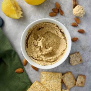 This is a photo of creamy almond dip overhead shot with almonds, lemon, and crackers.