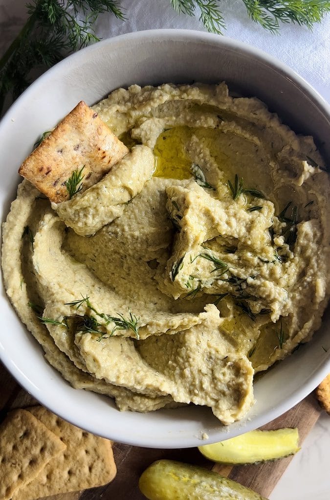 This is a picture of an overhead shot of creamy dill pickle hummus with a pita.