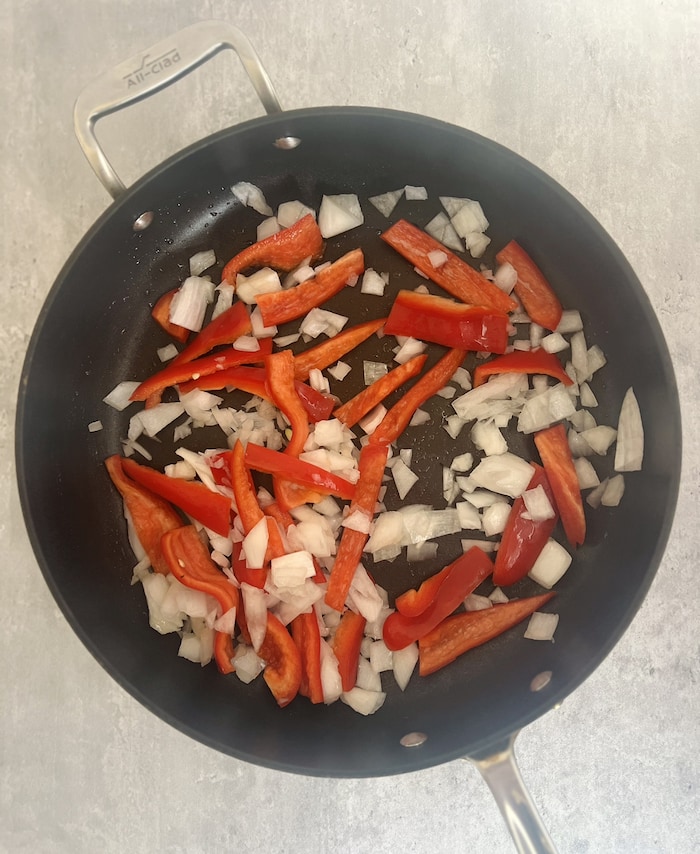 This is a picture of red peppers and onions in a pan. 