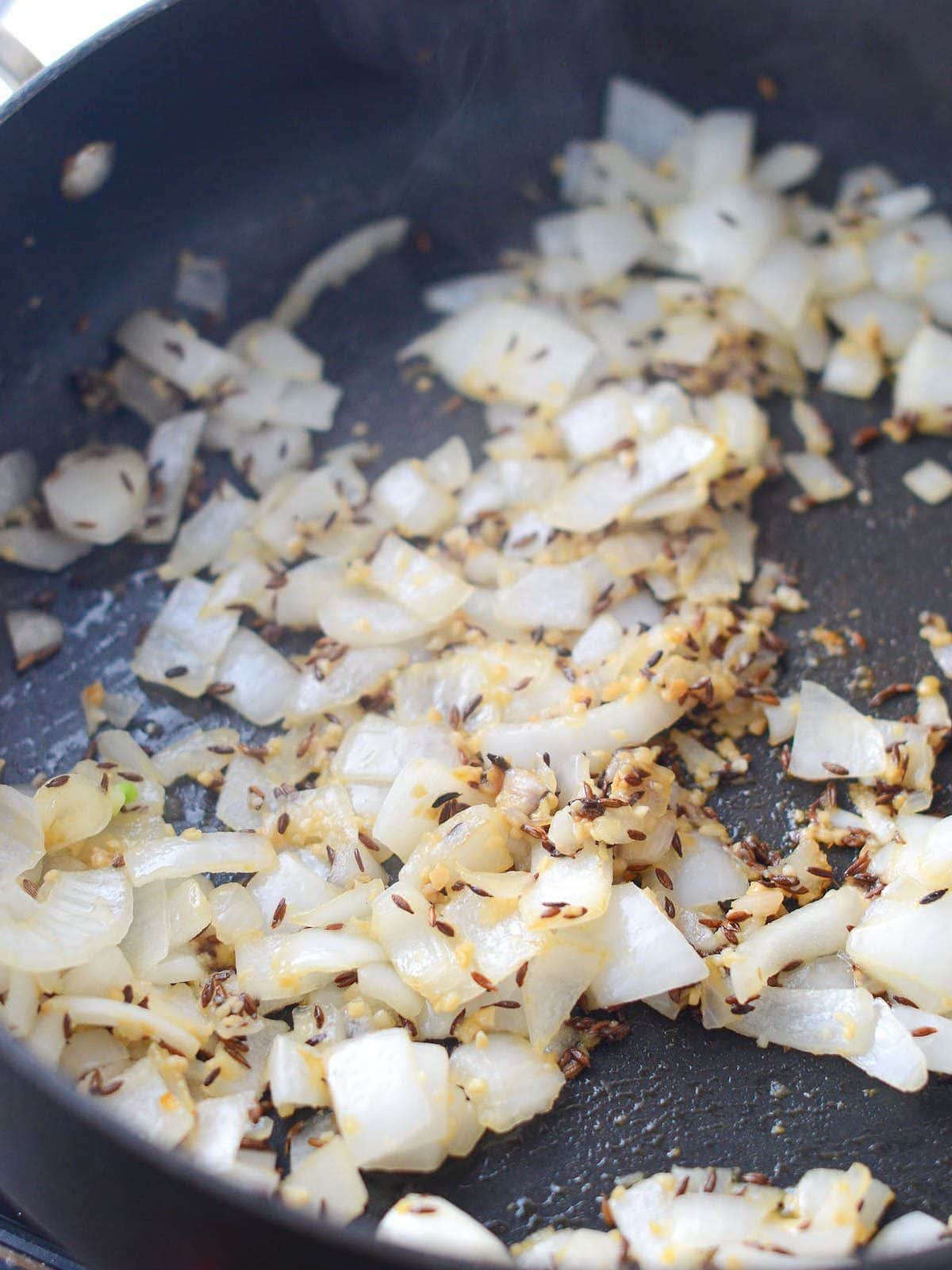 This is a photo of onions with garlic and ginger on the stove.