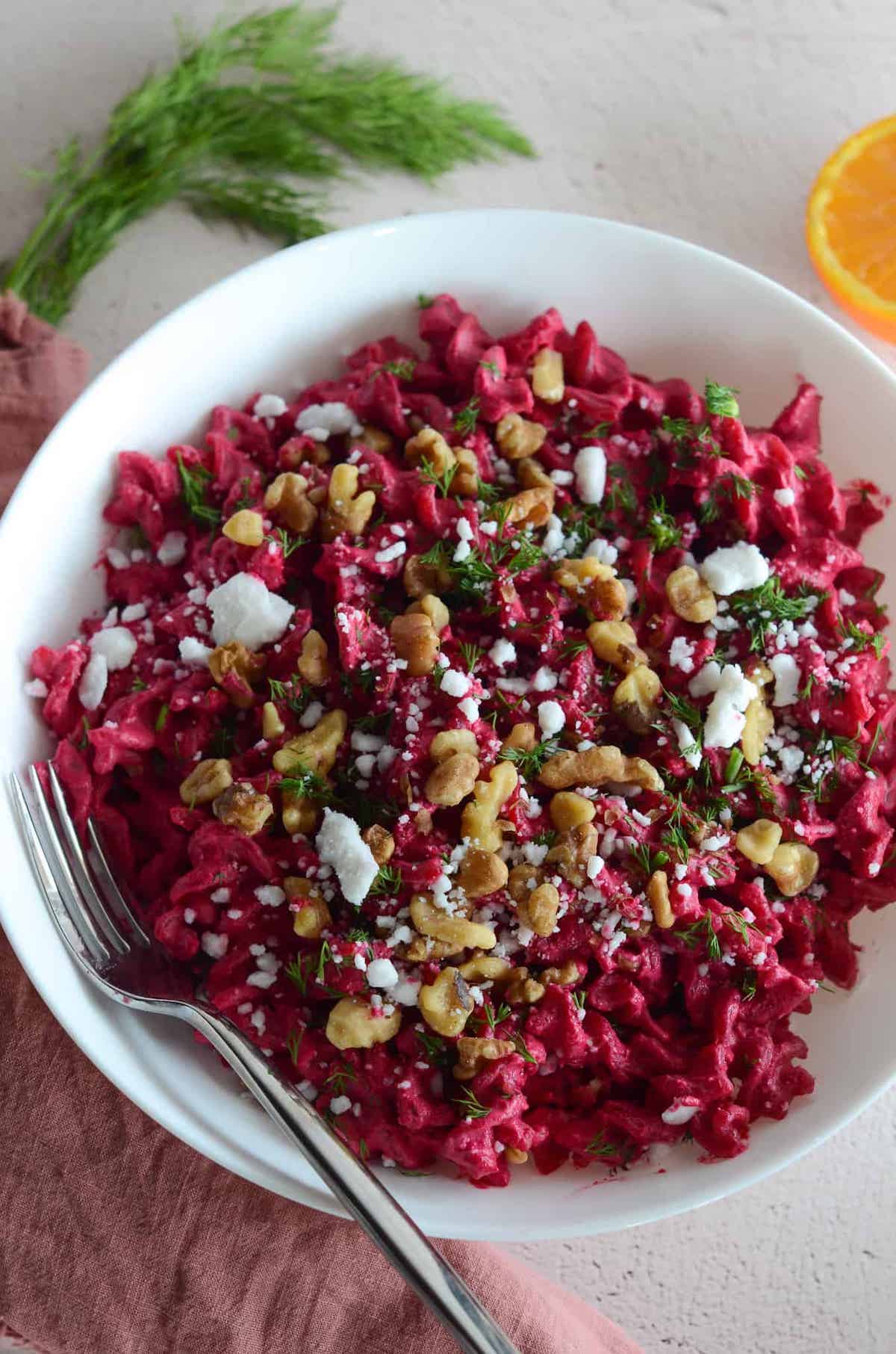 This is a photo of beet pasta sauce with walnuts, vegan feta, and dill.