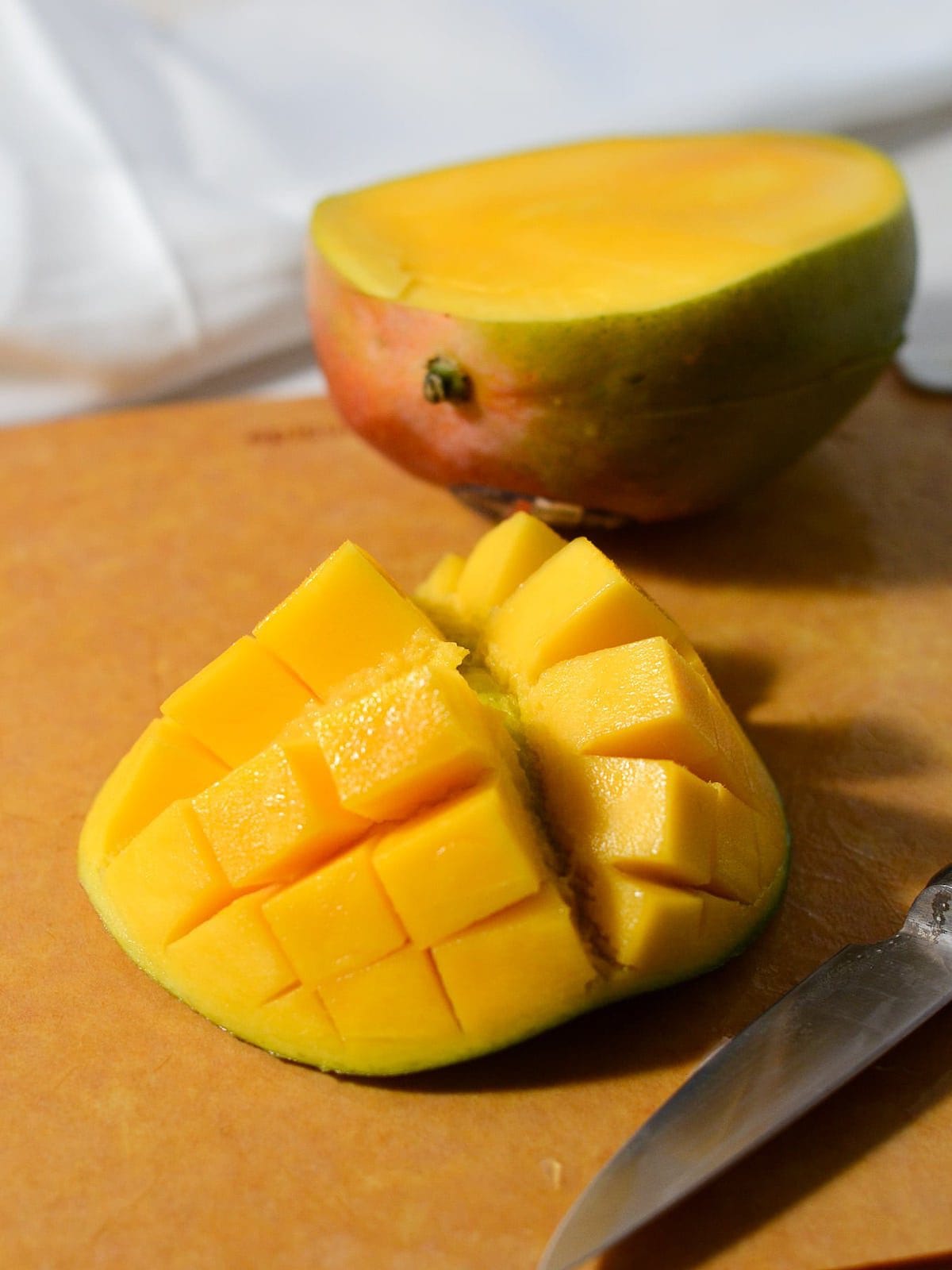 sliced mango on a cutting board with a knife. 