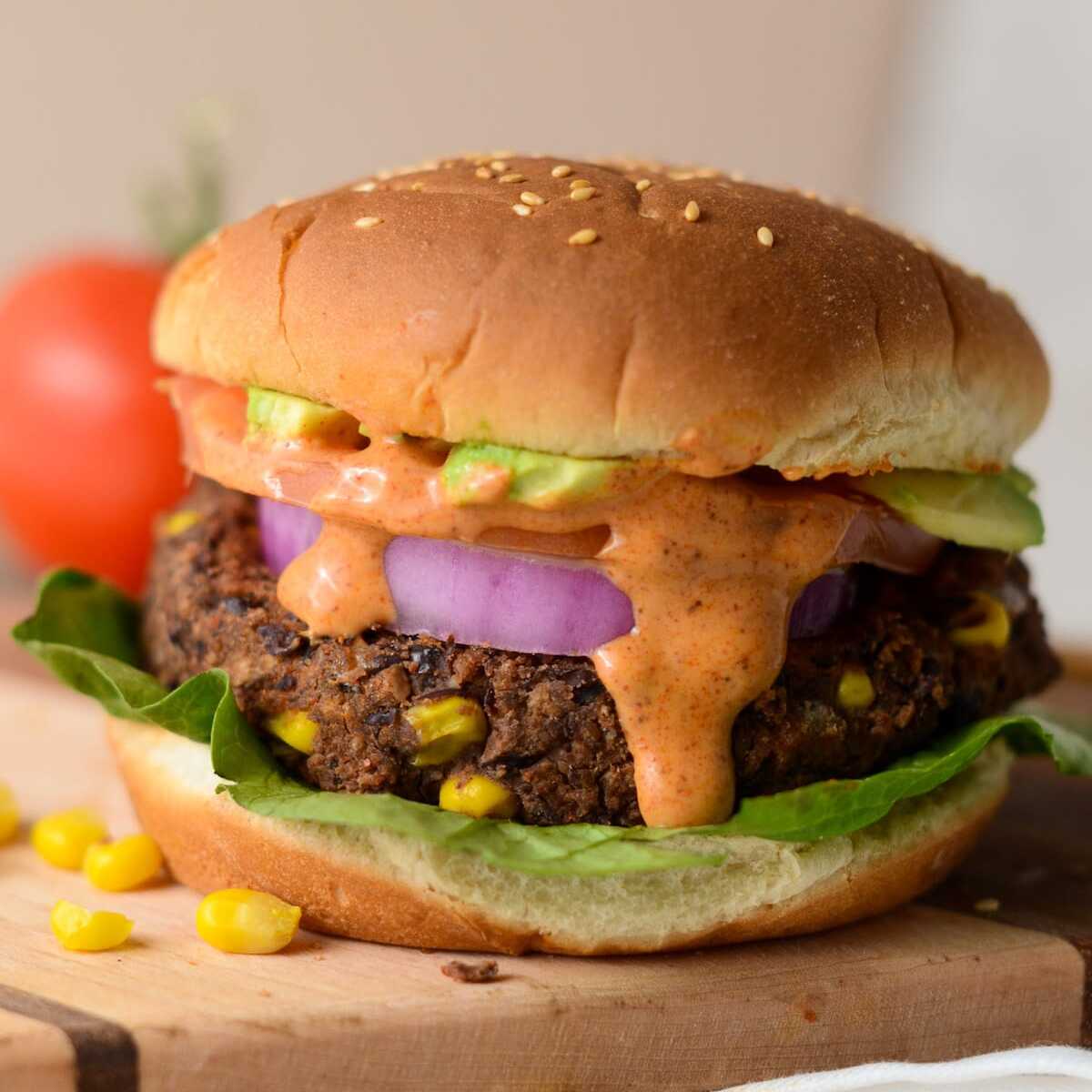 This is a photo of a black bean burger with burger sauce. 