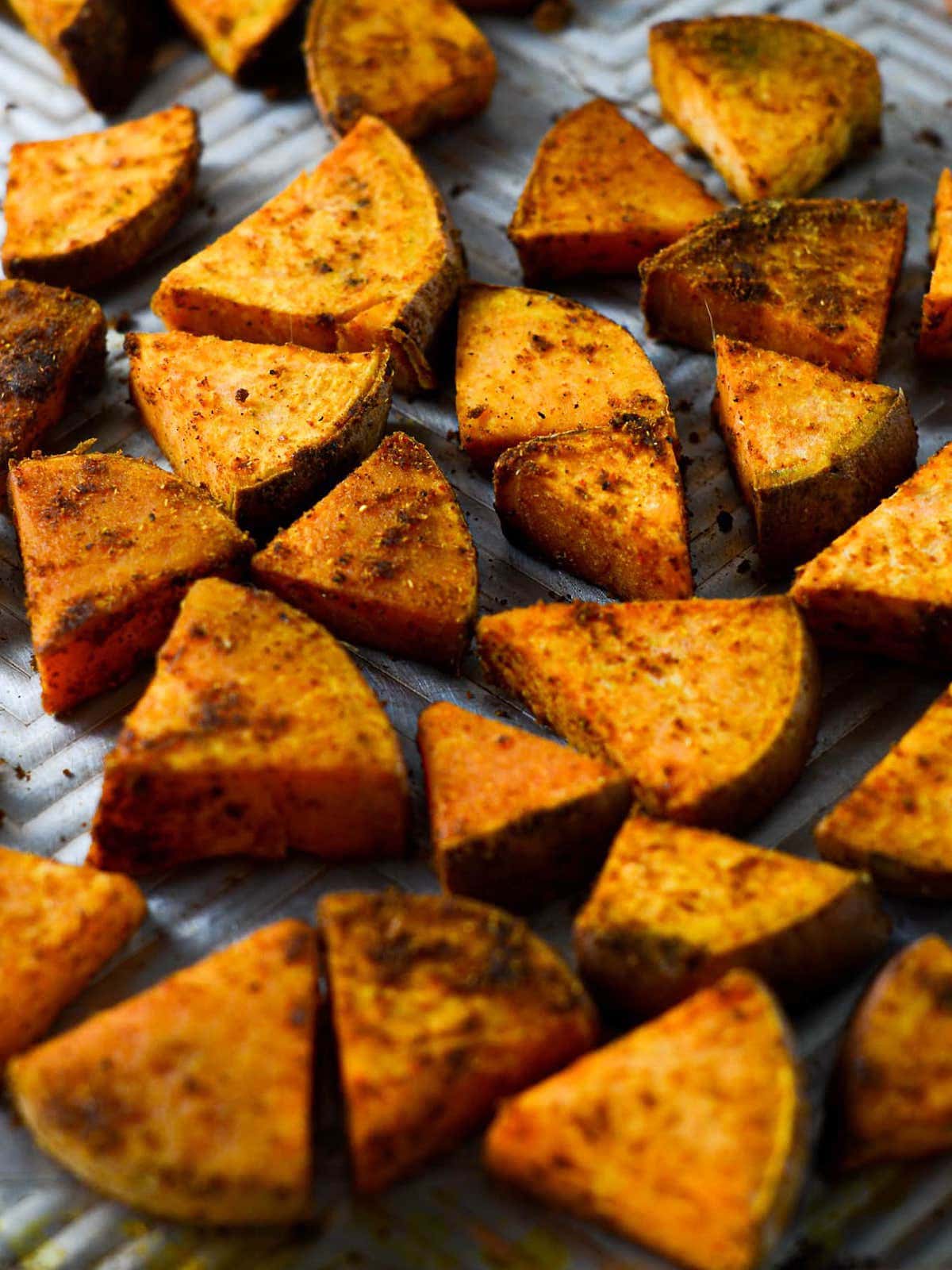 This is a photo of roasted sweet potatoes on a baking sheet, close up picture. 