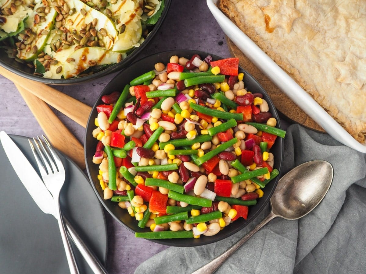 four bean salad in a bowl with fork and spoon on the side.