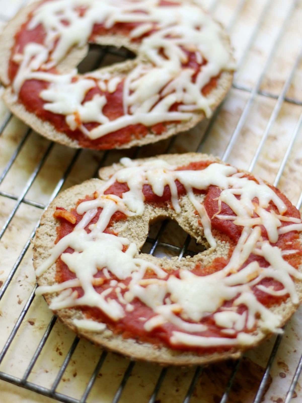 two pizza bagels on a baking tray. 