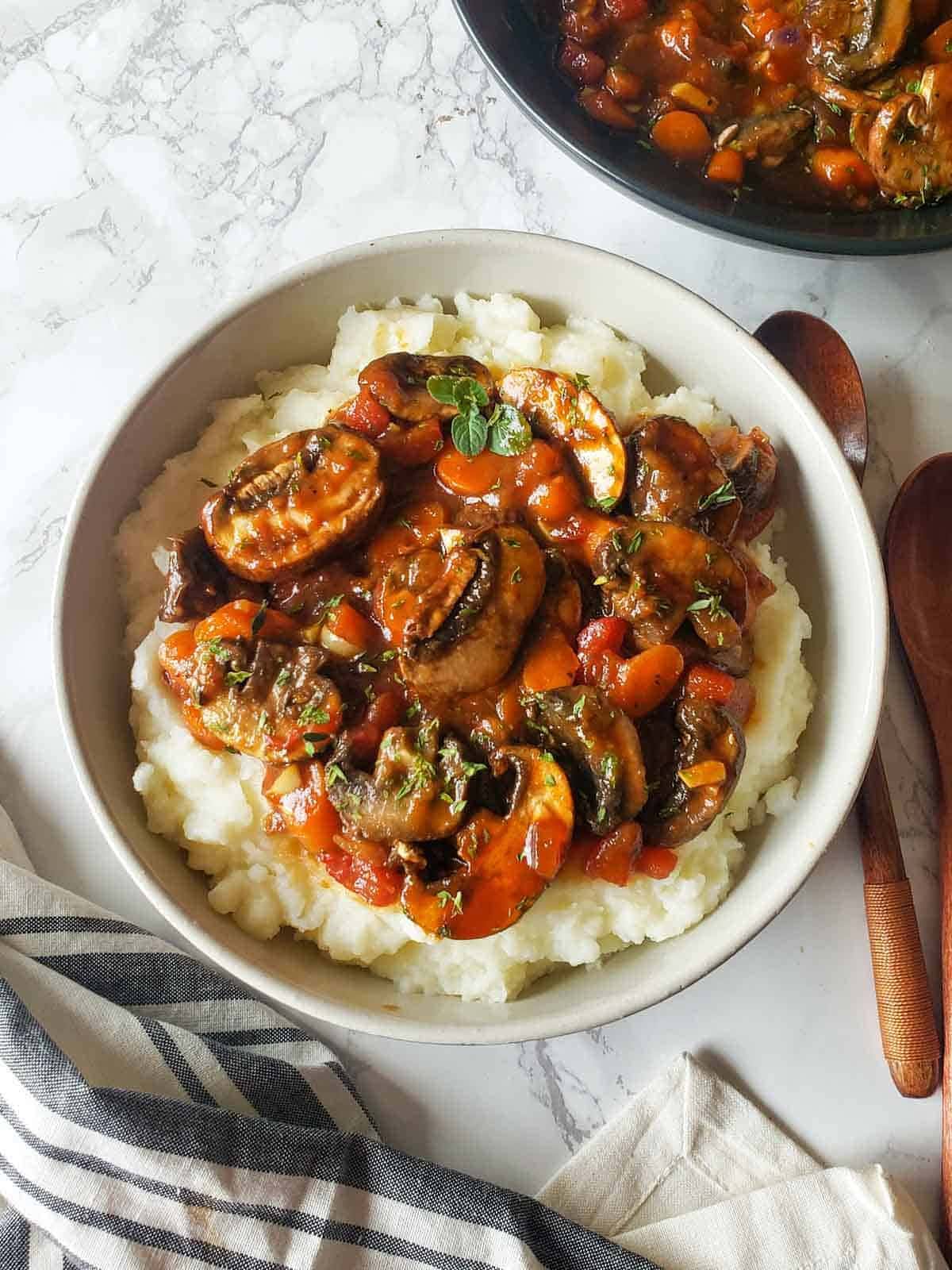 mushroom stew in a bowl with mashed potatoes beneath. 