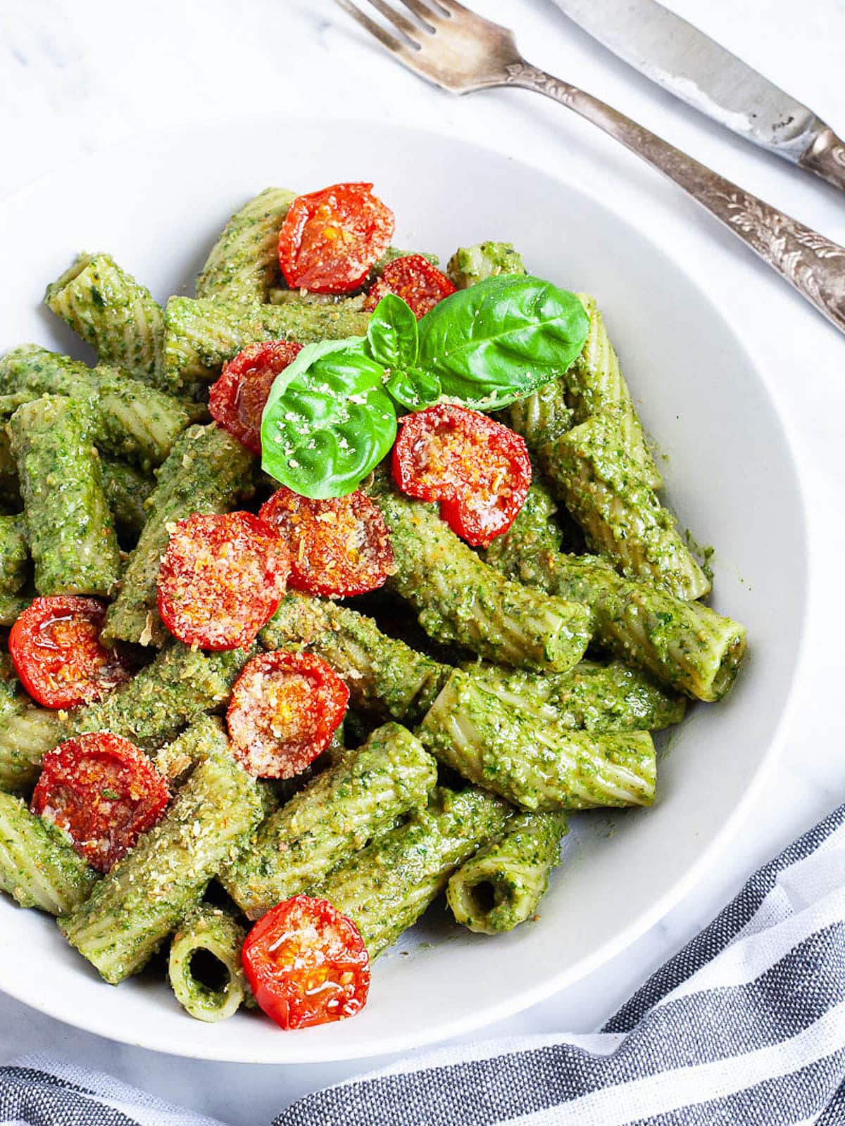 bowl of pesto pasta with tomatoes and basil.