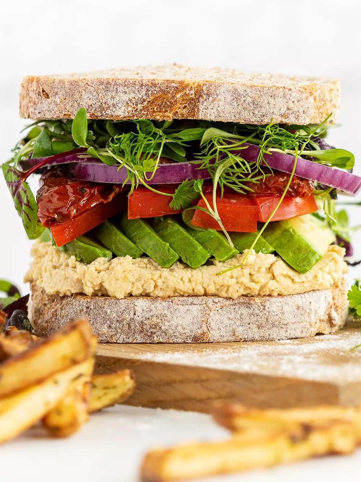a large avocado sandwich with french fries. 
