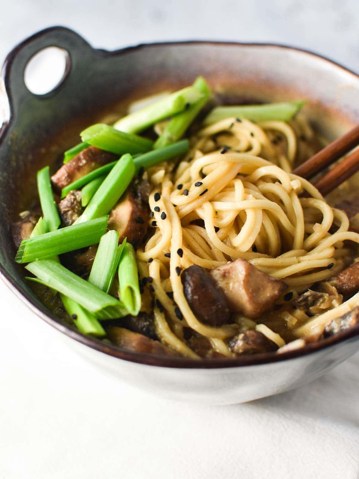 mushroom ramen in a bowl with noodles and green onion.