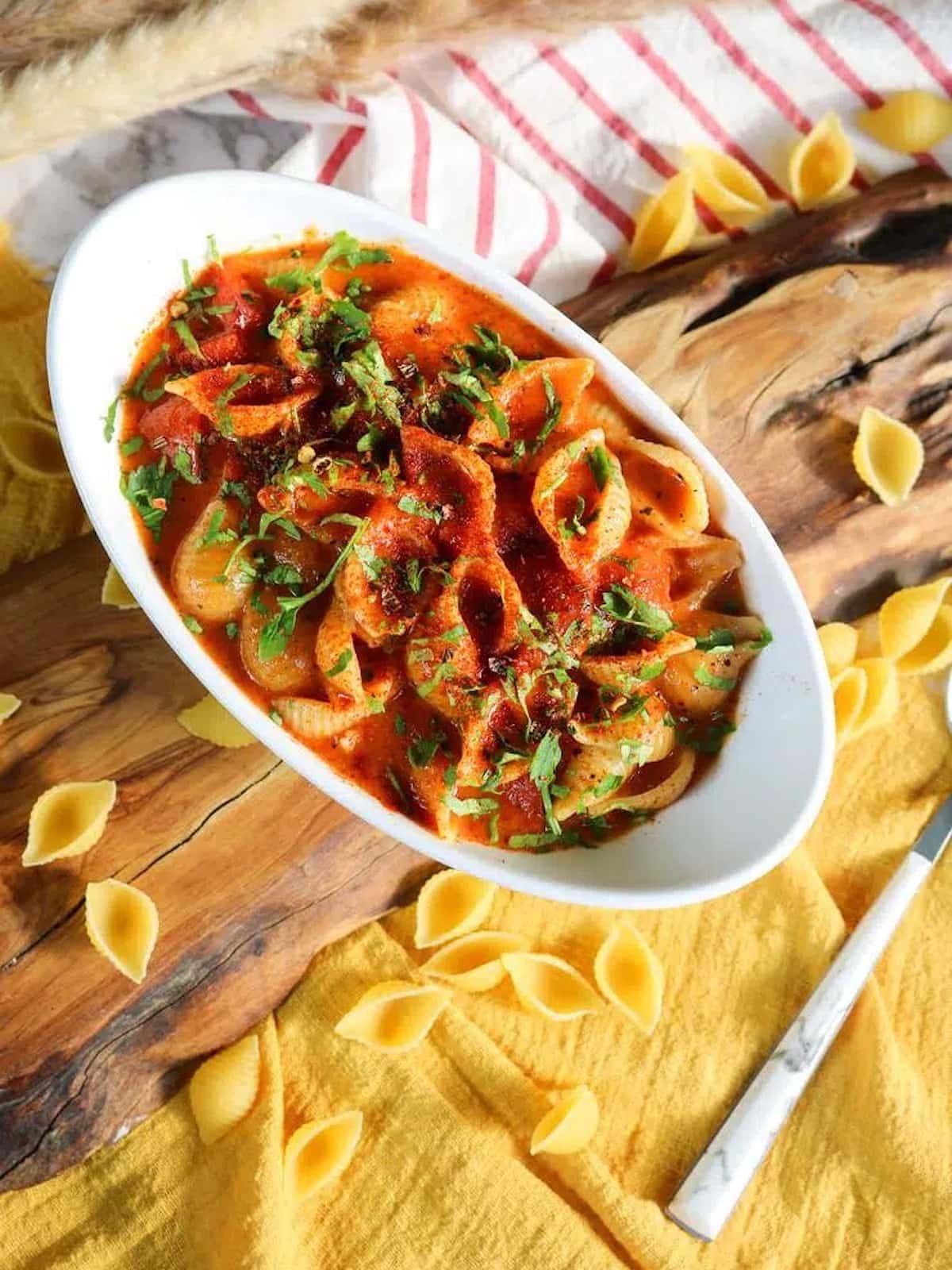 a bowl of cajun pasta. in a bowl with scattered noodles around it. 