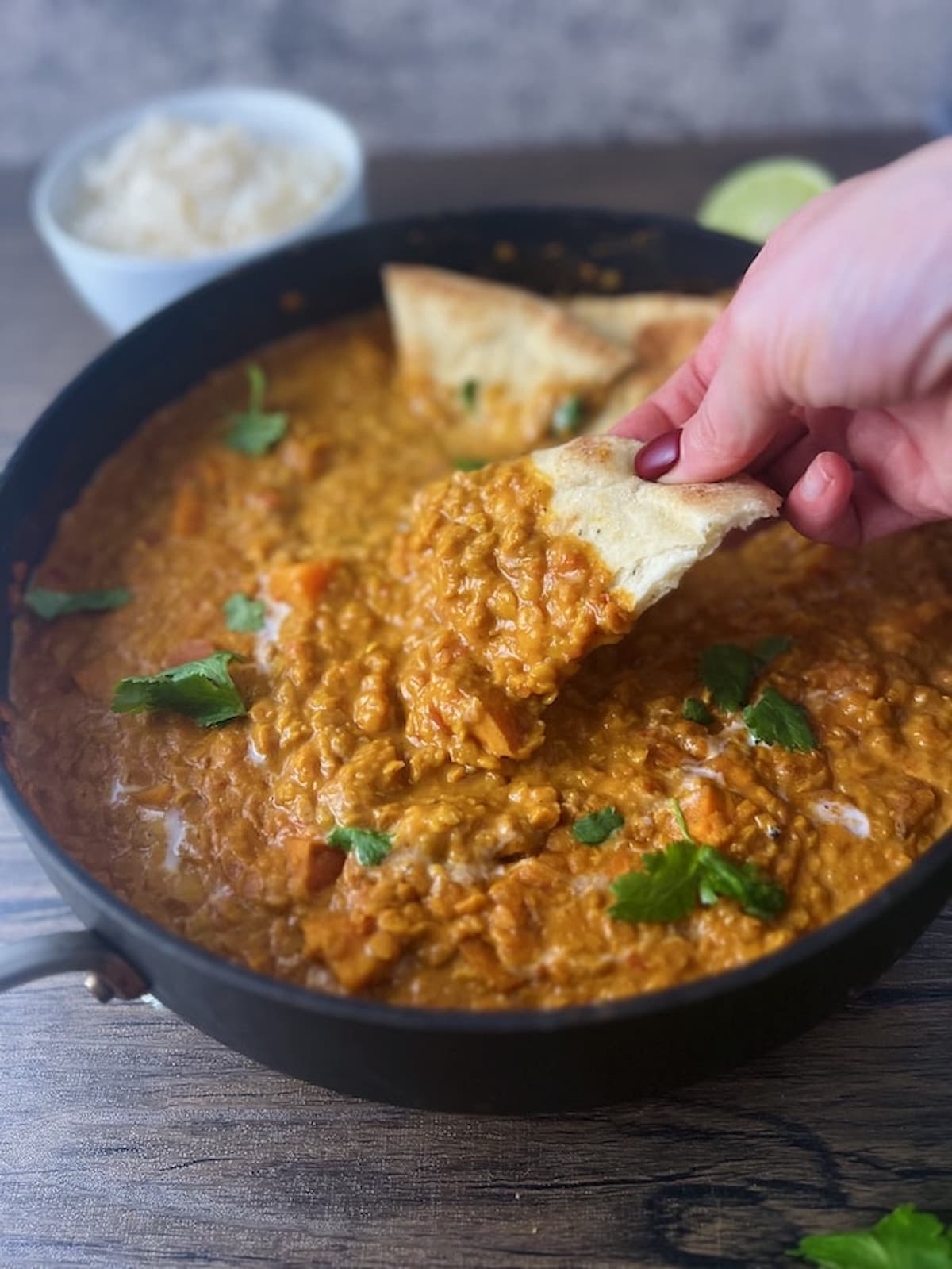 This is a photo of naan dipping into red lentil curry.