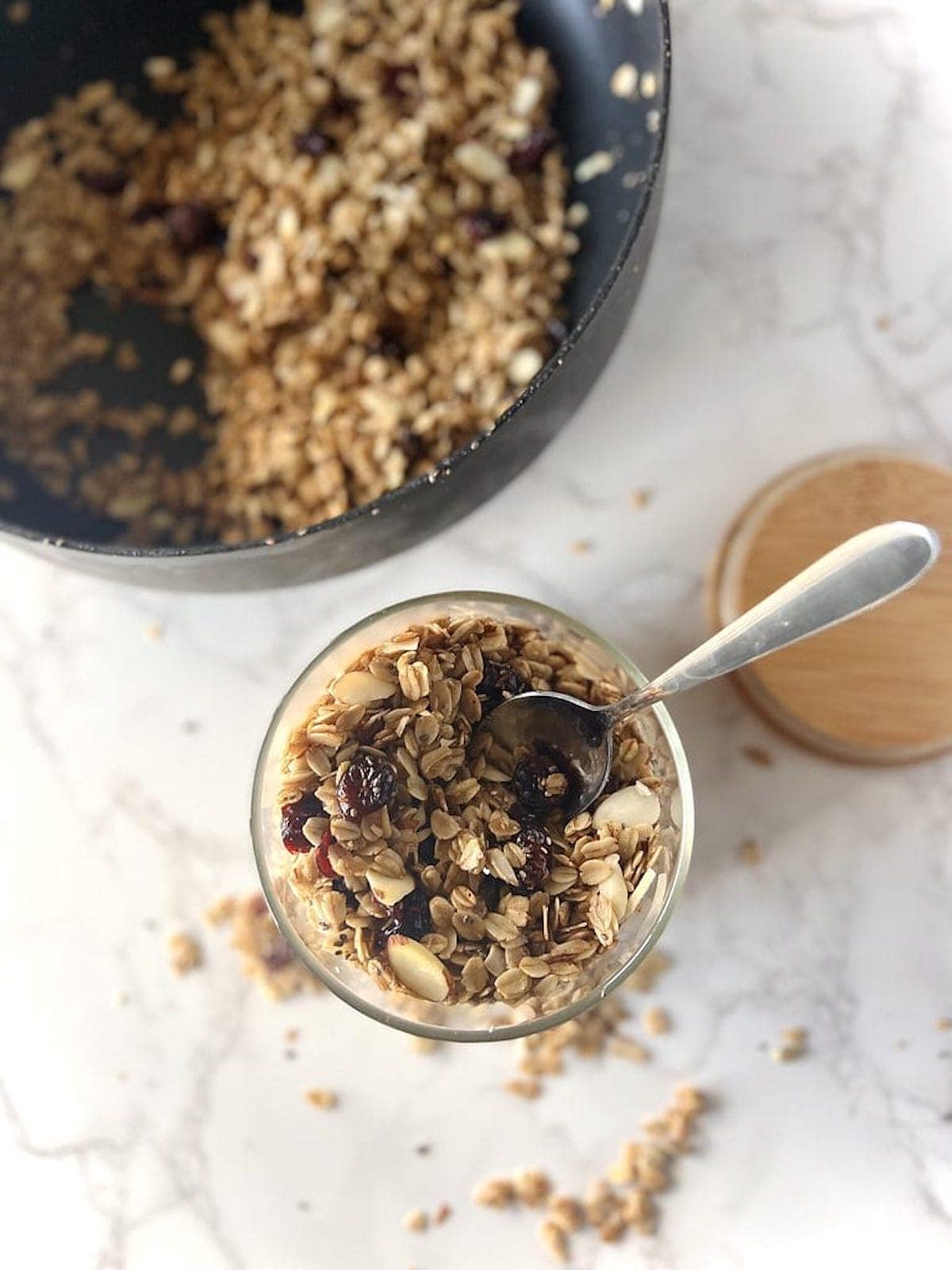 This is a photo of granola in a container with a spoon next to a pan. 