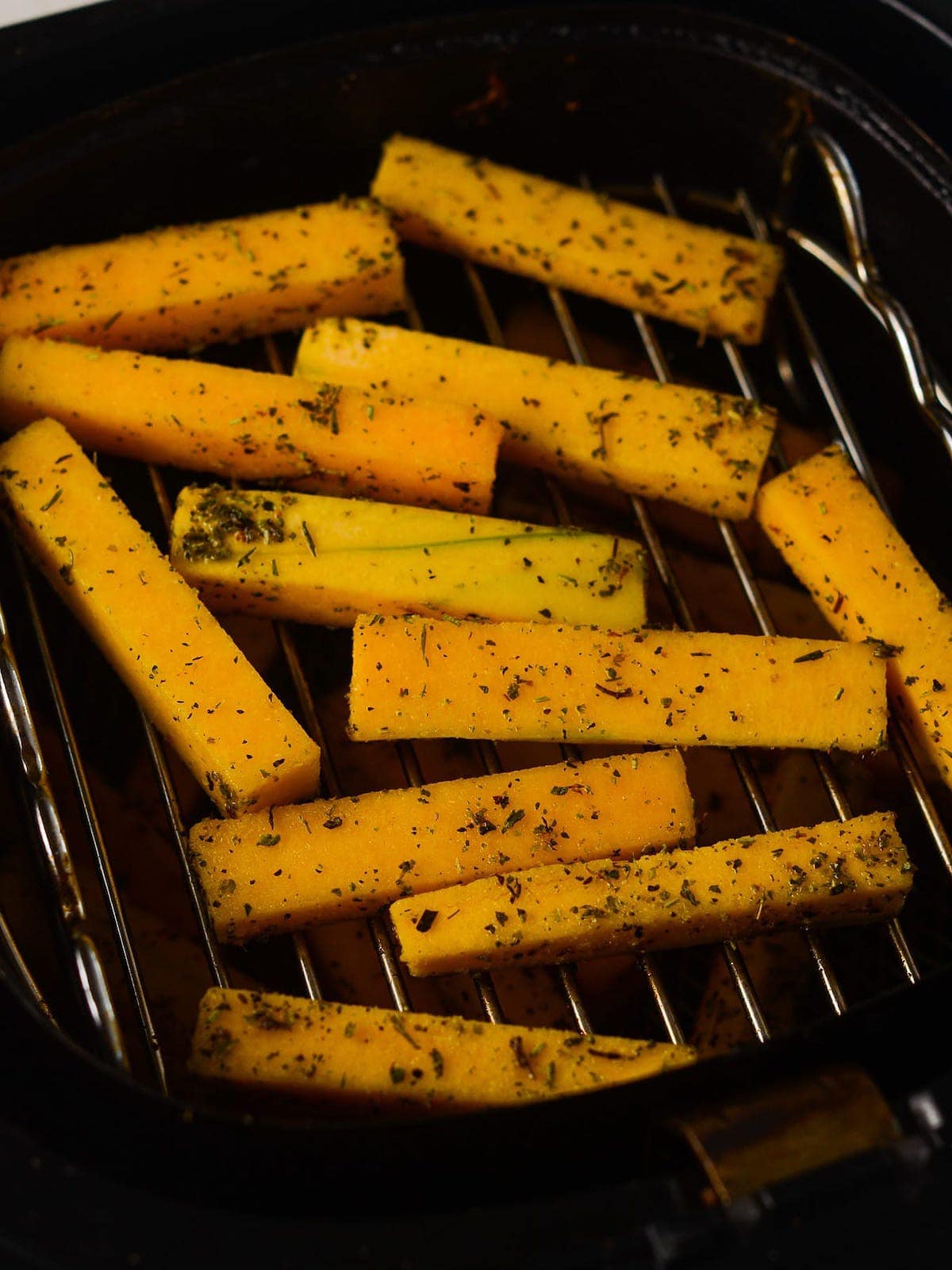 butternut squash fries in the air fryer basket, pre-cooked.