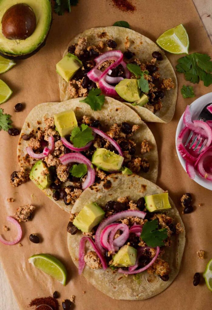 Overhead shot of tacos with limes and pickled onions