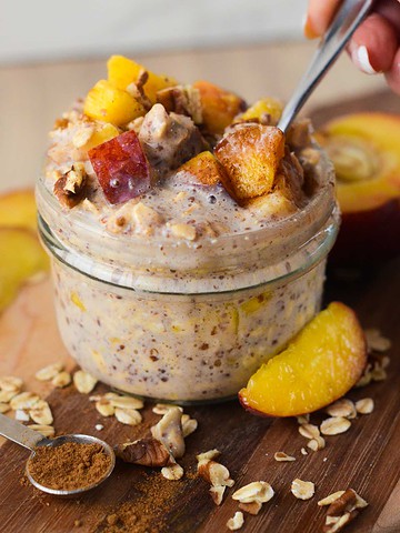 peach crisp overnight oats with a hand scooping up with a spoon