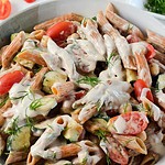 close up of red lentil pasta salad in a bowl with lemon