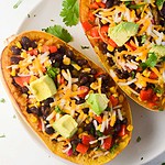 a photo of a stuffed squash (2) with limes on the side.