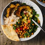 a spoon and piece of naan in a bowl of acorn squash curry.