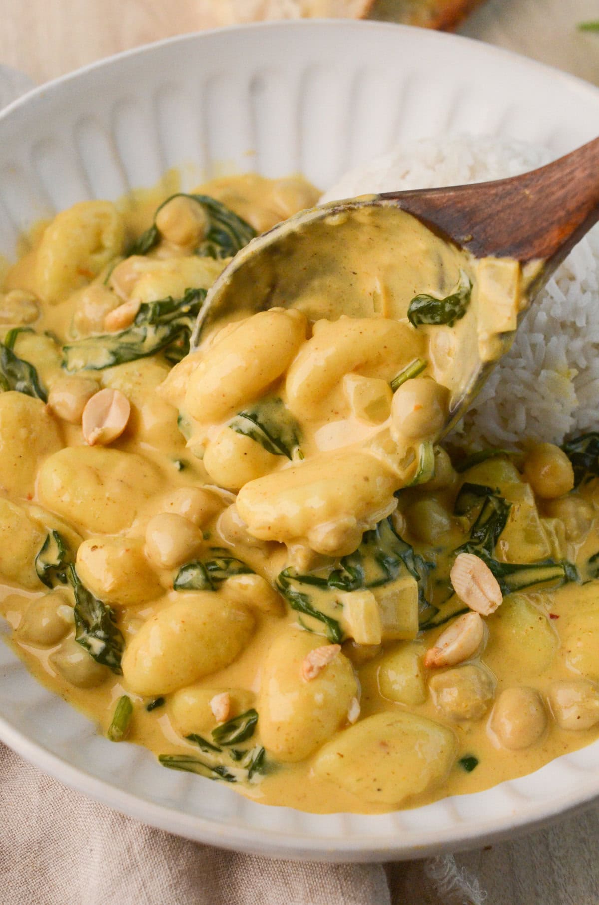 bowl of Coconut Curry Gnocchi with spinach, peanuts, and white rice