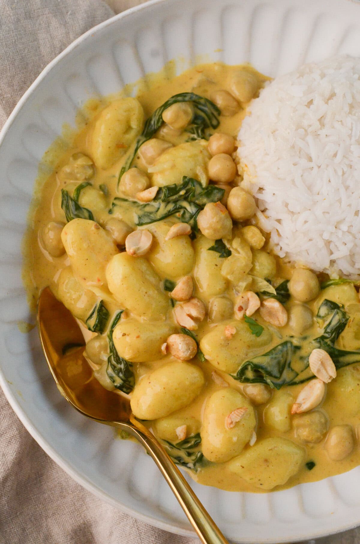 bowl of Coconut Curry Gnocchi with spinach, peanuts, and white rice