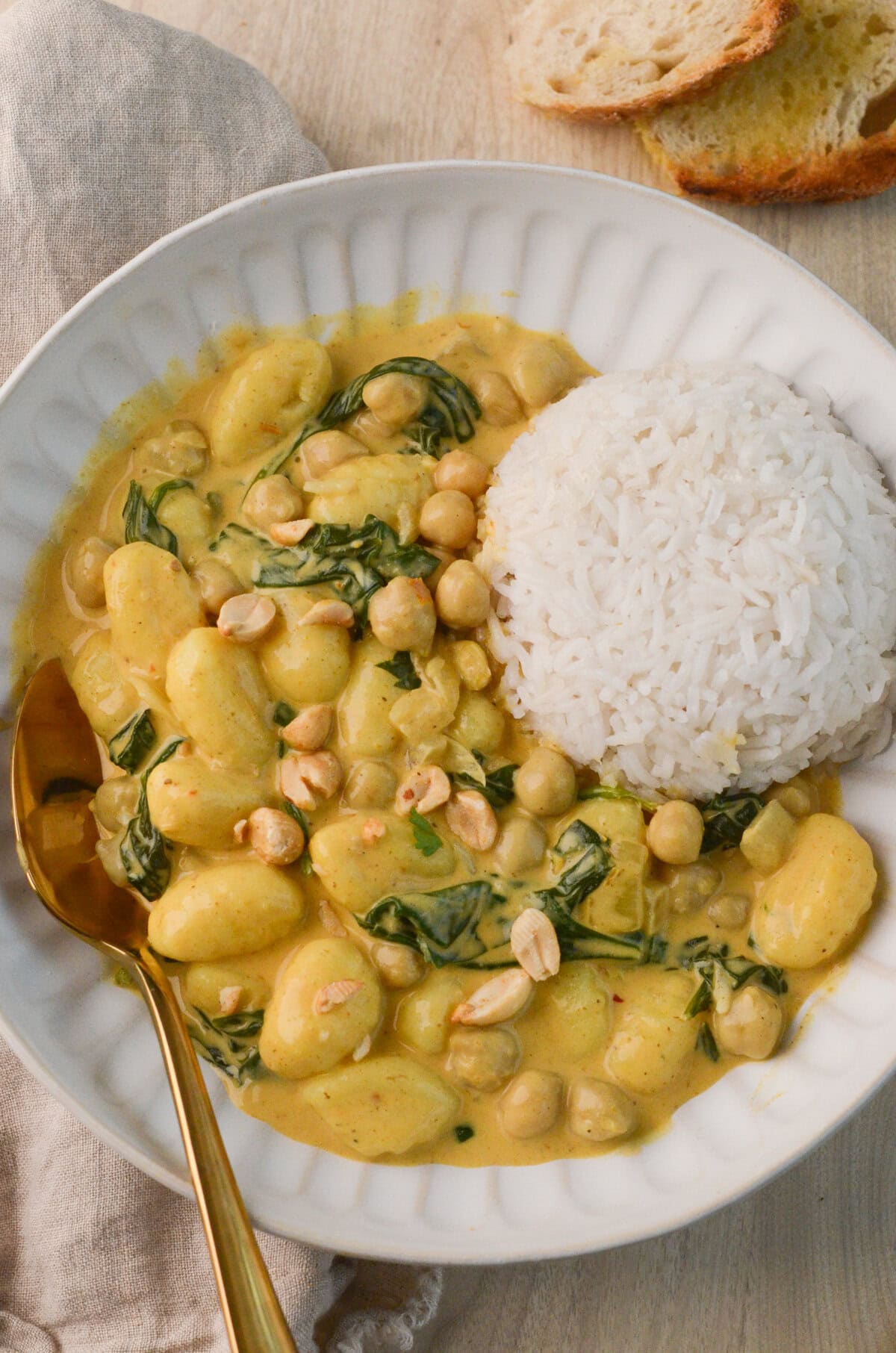 bowl of Coconut Curry Gnocchi with spinach, peanuts, and white rice
