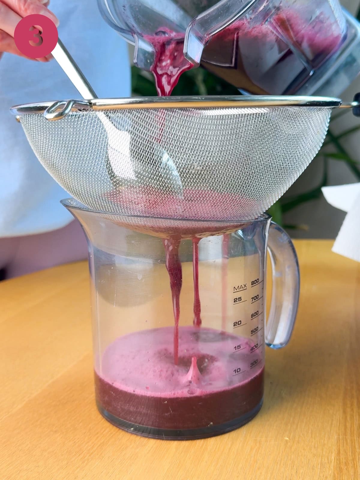 elderberry shots being strained through a strainer